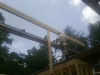 Carpenter setting a ridge beam over a new addition frame — Ice Dam Removal by Roofing Brothers in Duck River