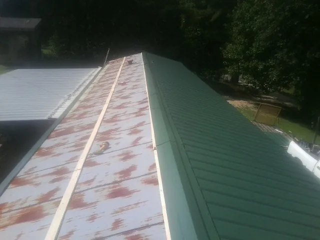 Old rusted panels beside newly installed green metal roofing — Wind Damage Roof Repair by Roofing Brothers in Duck River