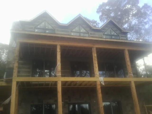 Dormers and porch framing on a large log home under construction — Roof Coating work by our crew in Duck River