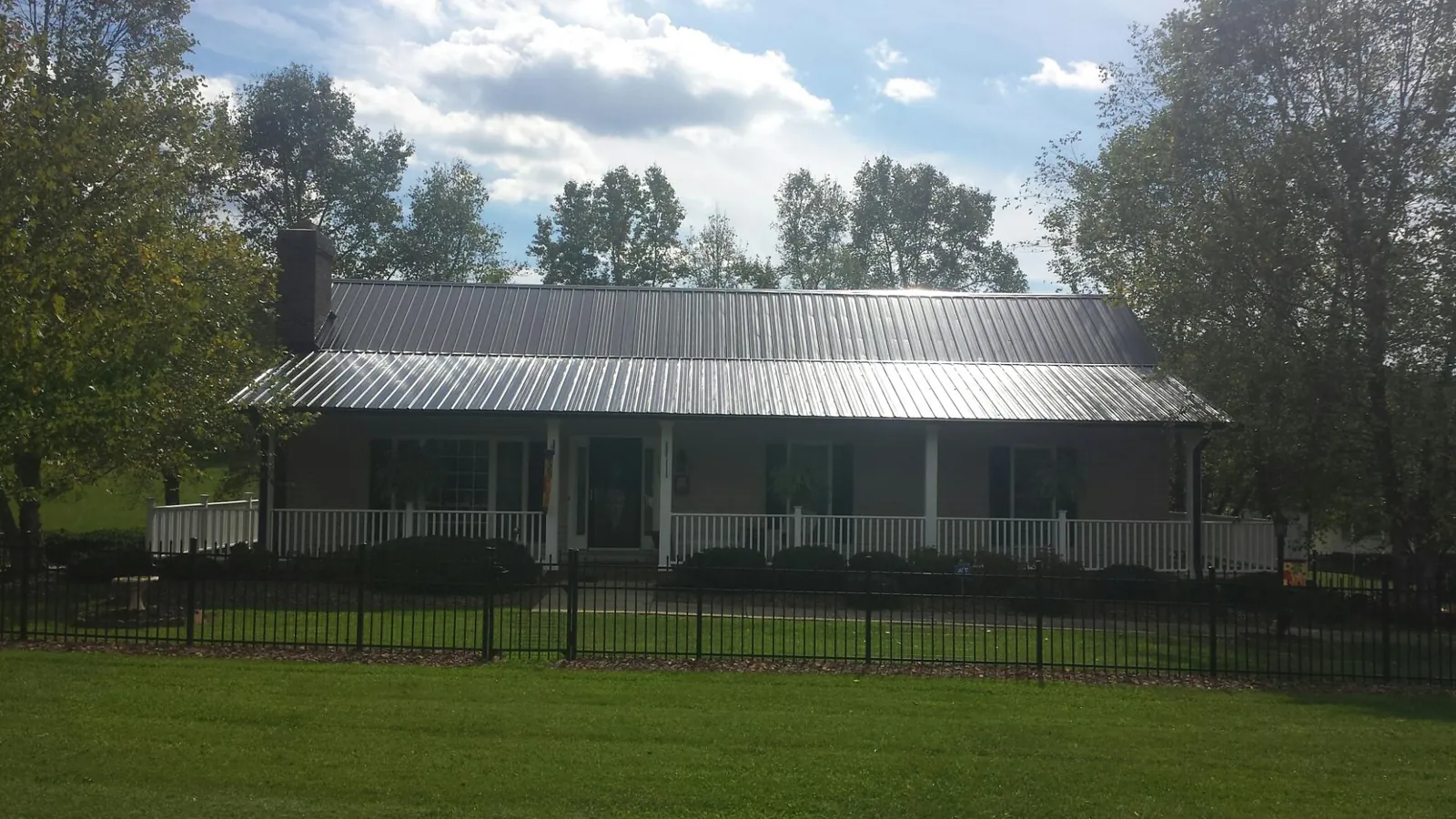 Gray metal roof on a brick ranch with a full width front porch — Gutter Guard Installation work by our crew in Duck River