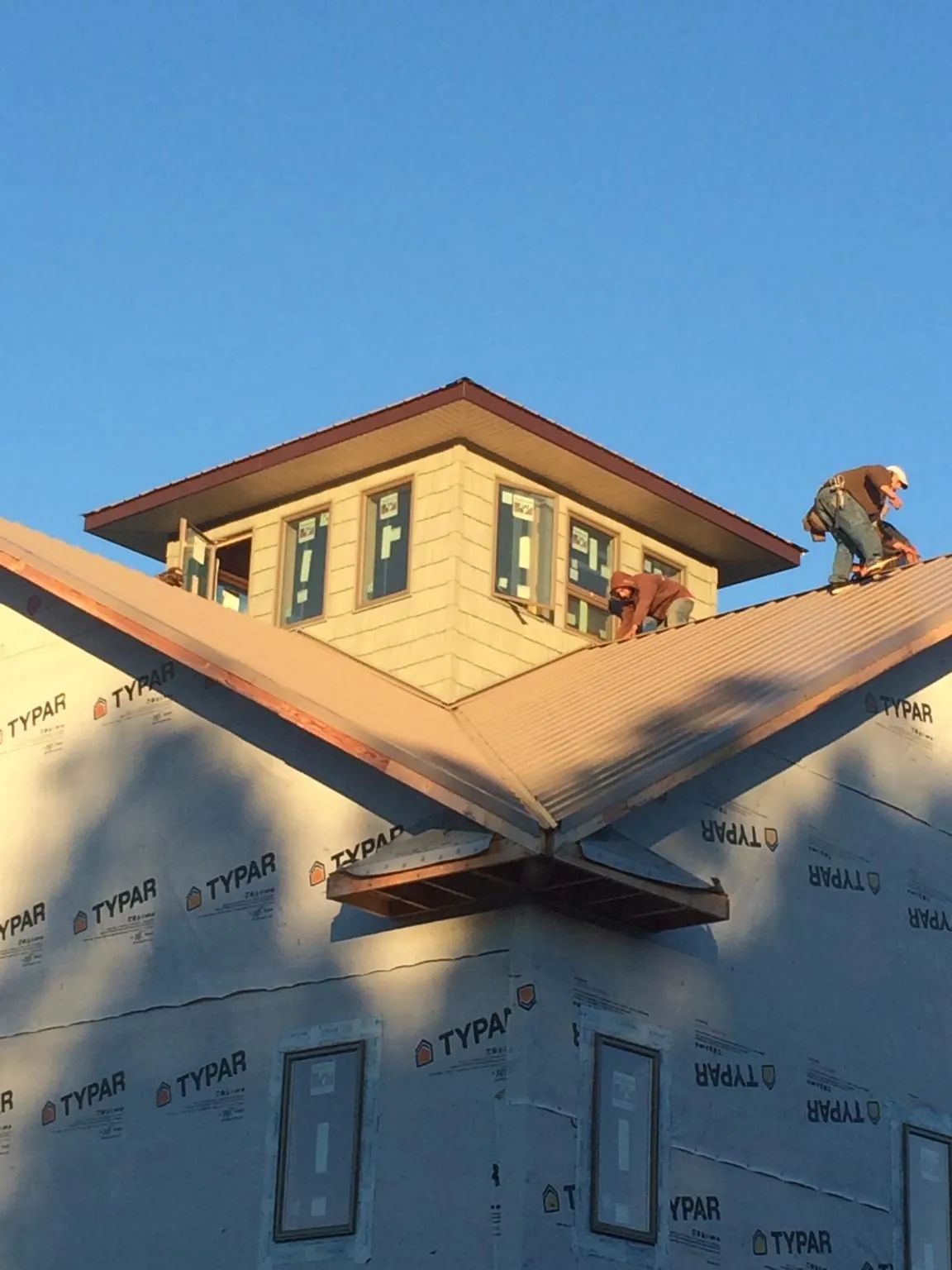 Roofers working around a rooftop cupola on a new metal roof at sunset — Roof Waterproofing in Duck River by Roofing Brothers